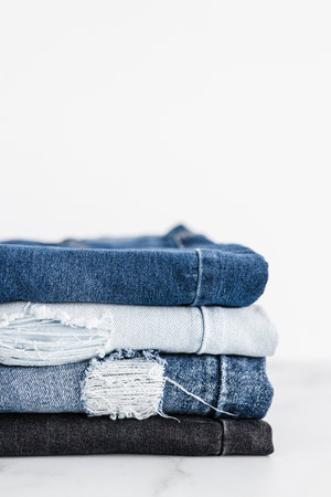 pile of jeans in different color denim fabric neatly folded and piled up on minimalistic backgroundの写真素材