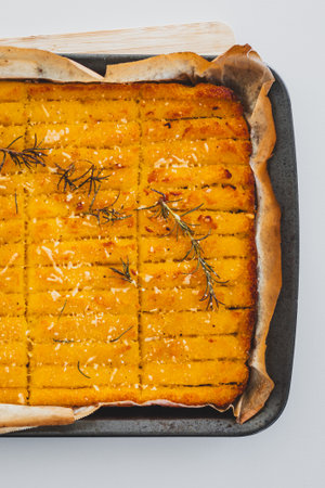 crispy golden polenta chips with rosemary roasted in the oven on a tray, delicious and homemade