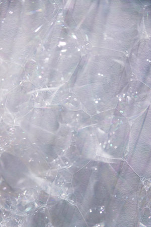 extreme close-up of soap bubbles on a white wall, ideal as background or texture overlayの写真素材
