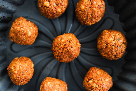 golden homemade chickpea falafels with spices on a black plate, healthy vegan food and home cooking