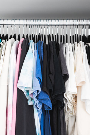 tidy organised wardrobe with matching flocked hangers and colour coded tops including shirts tees...