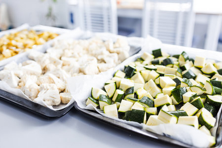 chopped cauliflower potato and zucchini on oven tray ready for roasting, healthy meal prep and vegetarian food themeの写真素材