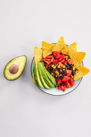 plate of healthy nachos with corn black beans tomato avocado and a few corn chips, vegetarian food...