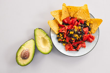 plate of healthy nachos with corn black beans tomato avocado and a few corn chips, vegetarian food...