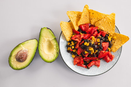 plate of healthy nachos with corn black beans tomato avocado and a few corn chips, vegetarian food...