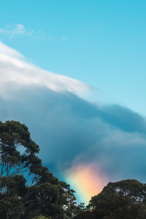 serene and whimsical image of a morning rainbow over the mountains and hills of tasmania, australia, no editing apart from color gradingの写真素材