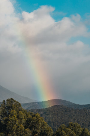 serene and whimsical image of a real morning rainbow over the mountains and hills of tasmania, australia, no editing apart from color gradingの写真素材