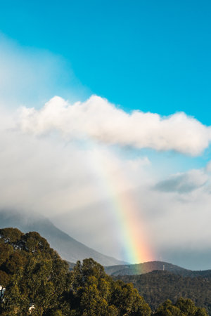 serene and whimsical image of a real morning rainbow over the mountains and hills of tasmania, australia, no editing apart from color gradingの写真素材
