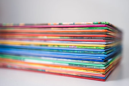 stack of colorful books for children on a white desk with shallow depth of field, representing early...