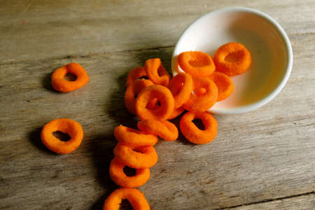 Cheese ring fall from small white plate on wooden background,の写真素材