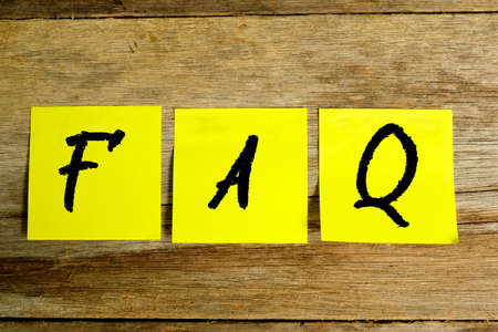 Top view of yellow sticky notes with words FAQ on wooden background.Concept for blog title and header.の写真素材