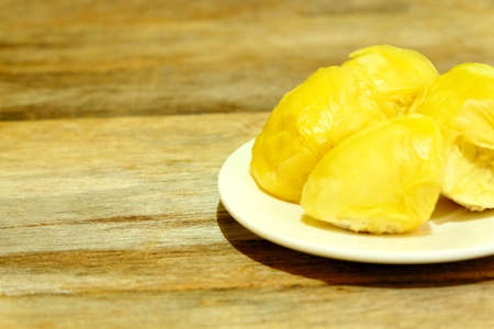Selective focus of durian fruit on white plate on rustic wooden table with copy space for text. Durian is delicious tropical and king of fruit, sweet and good smell. Ripe durian has yellow gold color.の写真素材