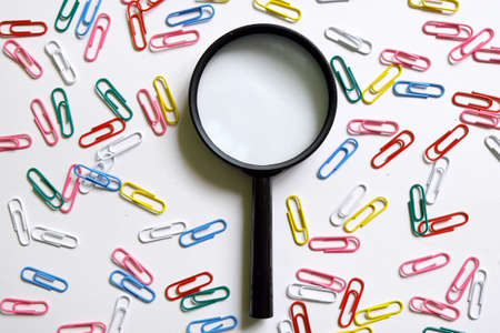 Colorful of paper clips and magnifying glass isolated on white background. Concept of...