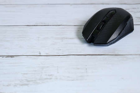 Selective focus of black wireless mouse on wooden background with copy space for text.の写真素材