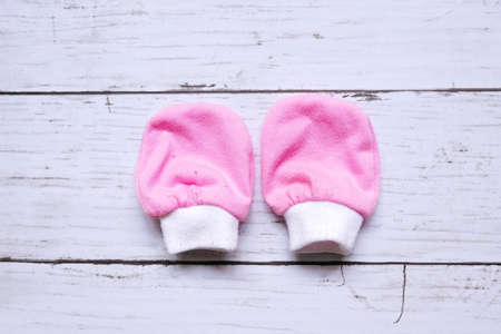 Top view of pink and white baby mitten on wooden background.の写真素材