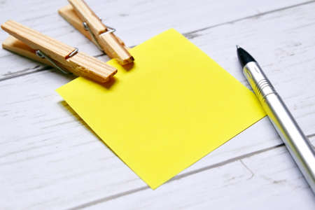 Miscellaneous theme. Top view of empty yellow sticky notes ,cloth pegs and pen on wooden background....