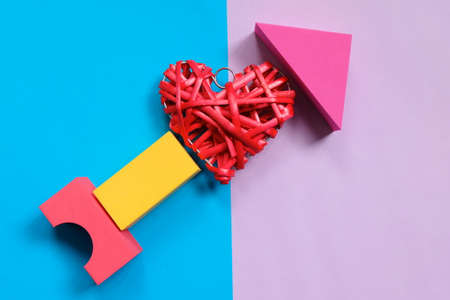 Top view of red wooden handcraft heart symbol with soft block symbolize arrow on blue and purple background. Two tone pastel background. Valentine's day theme.の写真素材