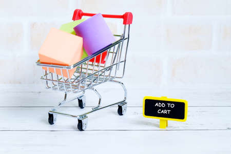 Selective focus of shopping cart or trolley with yellow blackboard written with 'ADD TO CART'. Shopping theme.の写真素材