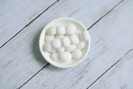 White naphthalene balls on white wooden background