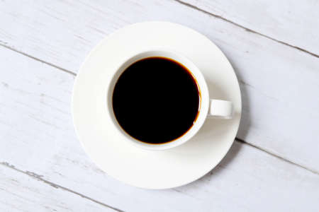 Top view of black coffee inside white cup on white wooden background.の写真素材