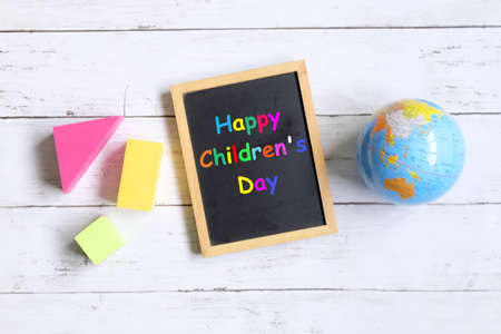 Top view of globe of world map,colorful soft block, and blackboard written with ' HAPPY CHILDREN'S DAY' on white wooden background.の写真素材