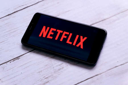 Kuala Lumpur,Malaysia - January 28th,2018 : Smartphone on a white wooden table with Netflix. Netflix specializes in and provides streaming media and video-on-demand online and DVD by mail.のeditorial素材