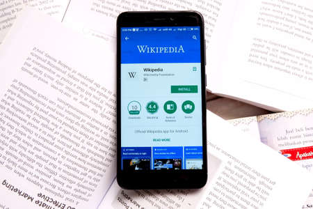 Kuala Lumpur,Malaysia - January 28th,2018 : Smartphone on an open books with wikipedia apps on android play store.Wikipedia is a free online encyclopedia with the mission of allowing anyone to edit articles.のeditorial素材