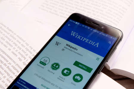 Kuala Lumpur,Malaysia - January 28th,2018 : Smartphone on an open books with wikipedia apps on android play store.Wikipedia is a free online encyclopedia with the mission of allowing anyone to edit articles.のeditorial素材