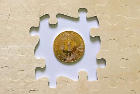 A golden bitcoin replica in between jigsaw puzzle. Business and finance concept.の写真素材