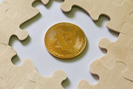 A golden bitcoin replica in between jigsaw puzzle. Business and finance concept.の写真素材