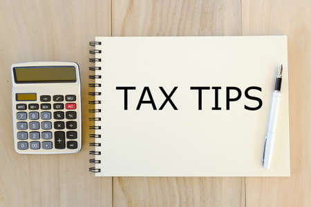 Business,finance and banking concept. Top view of calculator,pen and notebook written with Tax Tips...