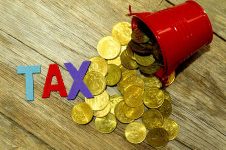 Word TAX with red pile of coins on wooden background.の写真素材