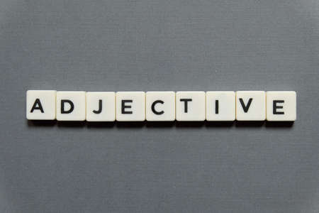 Adjective word made of square letter word on grey background.の写真素材