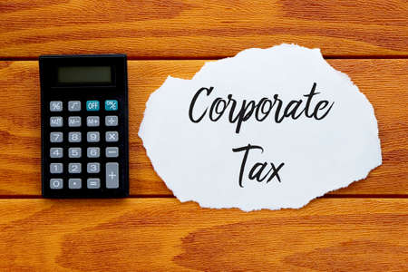 Top view of calculator and piece of paper written with Corporate Tax on wooden background,の写真素材