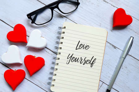 Glasses,wooden heart,pen and notebook written with Love Yourself.の写真素材