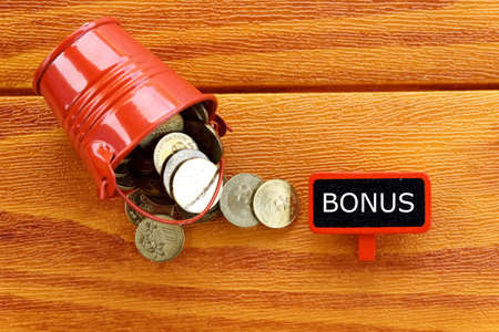 A pile of coins with blackboard written with Bonus on wooden background.の写真素材