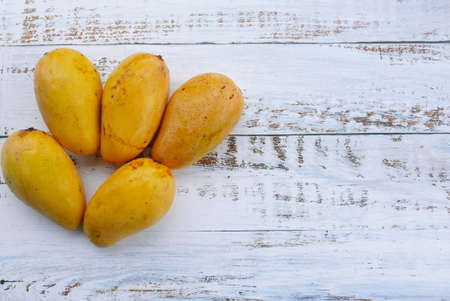Top view of Chok Anan or Chocanon mango on wooden background. Copy space for text or logo.