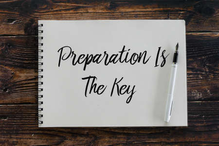 Top view of pen and notebook written with Preparation Is The Key.
