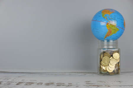 Globe over jar of coins. Money and world concept. Copy space for text and logo.の写真素材