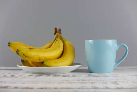 Bunch of bananas and a cup on wooden background.の写真素材