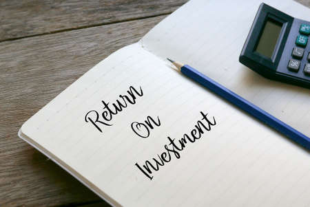 Calculator,pencil and notebook written with Return On Investment on wooden background.の写真素材