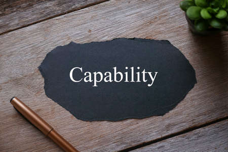 Pen,plant and piece of black paper written with Capability on wooden background.の写真素材
