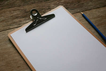 Writing board and white paper with stationery on wooden background. Copy space for text or logo.の写真素材