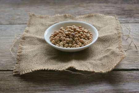 Soybeans in a white plate on rug sack on wooden background.の写真素材