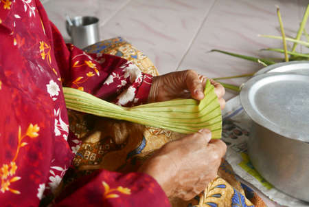 Selective focus of women making Ketupat, special dish served at Eid Mubarak / Ied Fitr celebration. Ketupat is made from rice packed.の写真素材