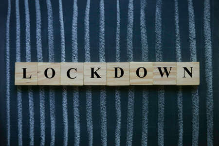 Selective focus of wooden cube written with Lockdown on a chalkboard with a line crossing on it represent the current situation of coronavirus or covid-19 issue. Lockdown or quarantine concept.の写真素材