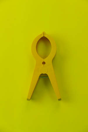Top view of a large yellow plastic clothes pin on a yellow background.の写真素材