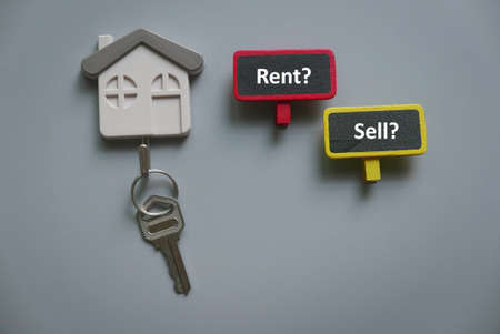 Top view of key holder with key and wooden notice board with question rent or sell.