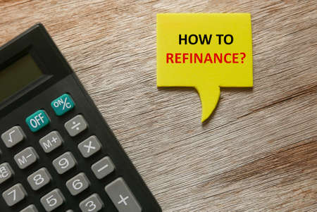 Top view of calculator, and yellow speech bubbles written with question of How to Refinance? on...