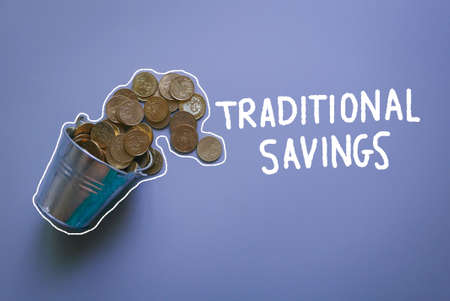 Top view of a stainless steel bucket full of gold coins on a grey background written with doodle of Traditional Savings. Concept of financial and business.の写真素材